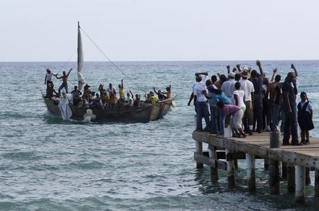 Cuban residents in the Cayman Islands (R) wave to migrants as they pass Grand Cayman Island on their way from Cuba towards Central America or the United States, off West Bay May 23, 2013. Cayman officials say a growing number of Cuban migrant boats are being spotted in its territorial waters as some Cubans worry about possible changes in U.S. immigration laws they fear could make it harder for them to enter that country. Picture taken May 23, 2013. REUTERS/Norma Connolly-CayCompass (CAYMAN ISLANDS - Tags: POLITICS SOCIETY IMMIGRATION) - RTX10CWS