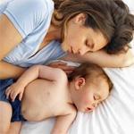 Fotografía de una mamá durmiendo con su bebé