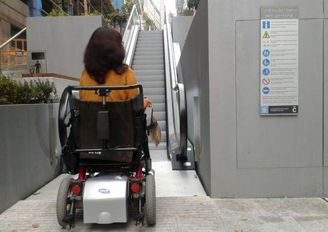 Una joven en silla de ruedas junto al cartel que especifica los usos.