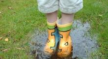 chico con botas de agua en un charco