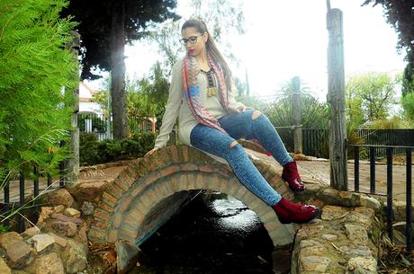 Maxi jersey asimétrico con vaqueros rasgados, botines burdeos, maxi bufanda y reloj