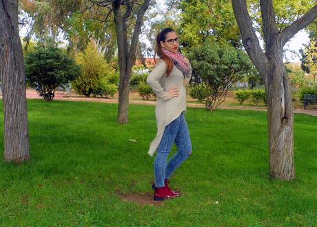 Maxi jersey asimétrico con vaqueros rasgados, botines burdeos, maxi bufanda y reloj