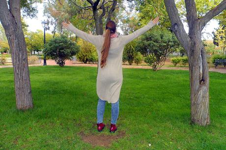 Maxi jersey asimétrico con vaqueros rasgados, botines burdeos, maxi bufanda y reloj