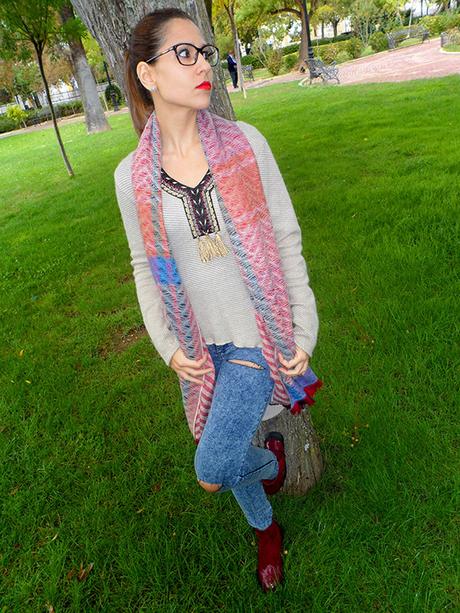 Maxi jersey asimétrico con vaqueros rasgados, botines burdeos, maxi bufanda y reloj