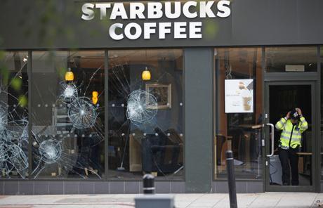A policeman comes out of Starbucks cafe in the area of Clapham in the aftermath left by riots in London Tuesday, August 9, 2011.