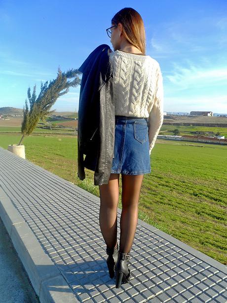 Falda denim acamapanda, jersey de punto rasgado, cazadora biker negra y botines de tacón con hebillas