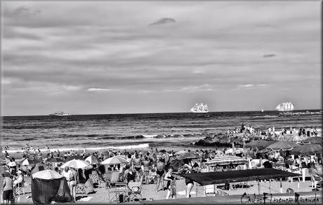 Blanco y negro.Gente en la playa y barcos en horizonte.