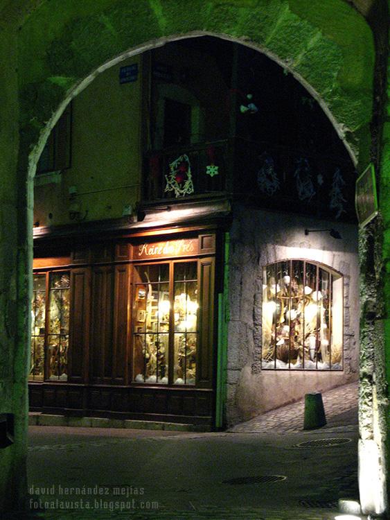 Vista de una calle de Annecy, Francia, de noche a través de un arco de piedra en época navideña