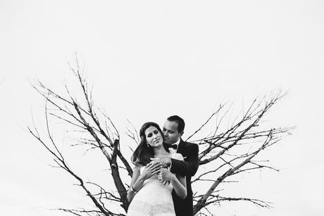 Abrazo entre los novios con árbol de fondo