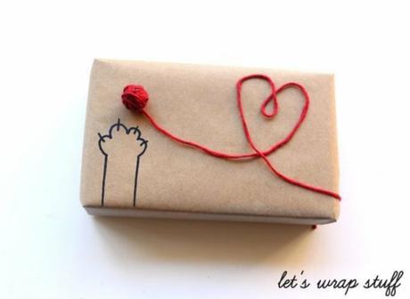 Envoltorio de regalo con papel kraft y corazón ovillo de lana y garra de gato dibujada