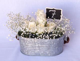 Cubo de cinc con rosas blancas, paniculata y número de mesa en pizarra