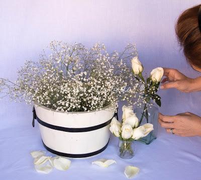 Bodegón con cubo de paniculata y recipientes de cristal con rosas