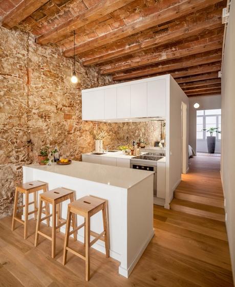 revestimiento de piedra y madera Reformas Barcelona pisos diáfanos estilo nórdico espejo bajo los armarios superiores distribución diáfana cocina abierta moderna blog decoración nórdica 