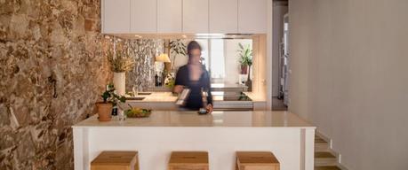 revestimiento de piedra y madera Reformas Barcelona pisos diáfanos estilo nórdico espejo bajo los armarios superiores distribución diáfana cocina abierta moderna blog decoración nórdica 