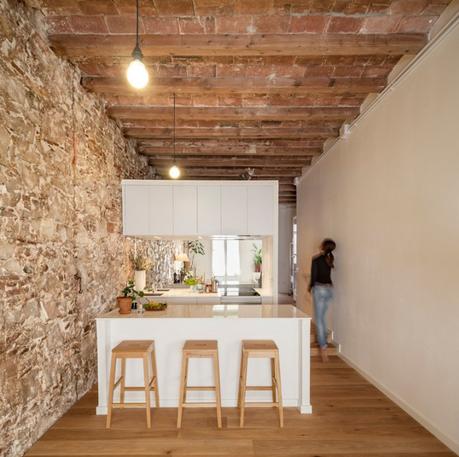 revestimiento de piedra y madera Reformas Barcelona pisos diáfanos estilo nórdico espejo bajo los armarios superiores distribución diáfana cocina abierta moderna blog decoración nórdica 