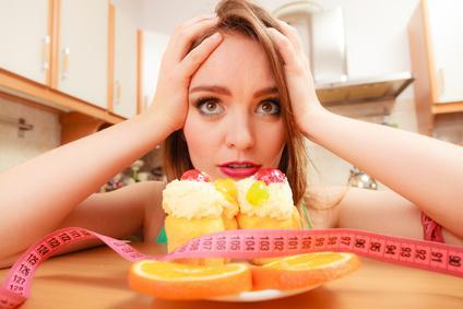 Undecided woman looking at delicious cake with sweet cream and fruits on top. Girl with tape measure trying to resist temptation. Slimming diet dilemma.