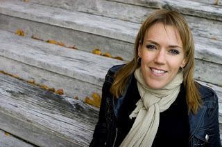 Escritora sueca Asa Larsson, mujer rubia de piel blanca, con chaqueta tipo cuero y bufanda beig.