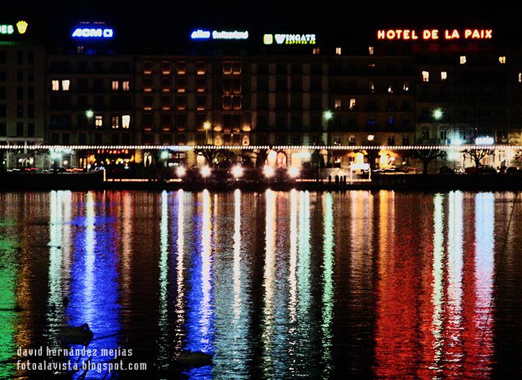 Reflejos en la noche de las luces de los edificios y hoteles de Ginebra (Suiza) sobre el lago Lemán