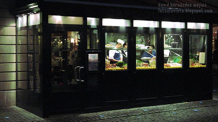 Vista a través de la cristalera del interior de un restaurante en Ginebra (Suiza) con los camareros y cocineros trabajando