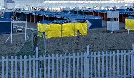Una pequeña cancha de fútbol de piso de arena y dos pibes jugando en la playa..