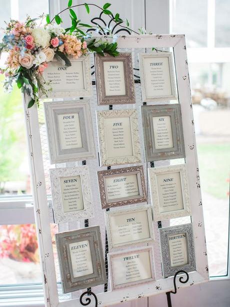 Seating chart at a wedding with chicken wire and frames mounted on it with table numbers: 