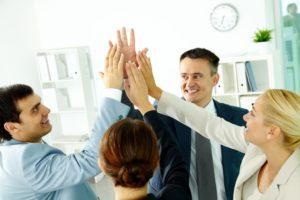 Resolución de conflictos laborales en la empresa Imagen de un grupo de trabajadores chocando las manos, todos felices y en equipo