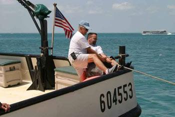 Miembros de la tripulación cubano estadounidense del “Santrina”, con licencia de Estados Unidos no. 604553, y portando la bandera estadounidense, tratan de sacar su bote a seguro. Foto: D.R. 2005 Mario Alonzo, Por Esto!