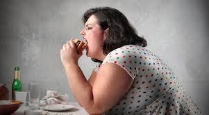 mujer obesa comiendo una hamburguesa