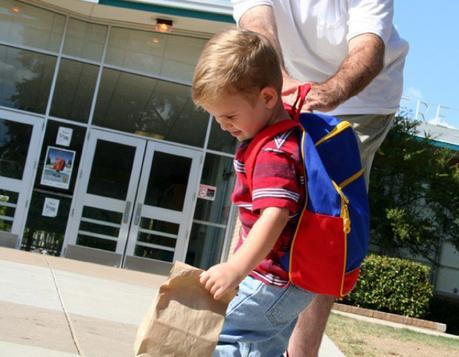 Imagen de niño resignado entrando al colegio, separándose de su padre.
