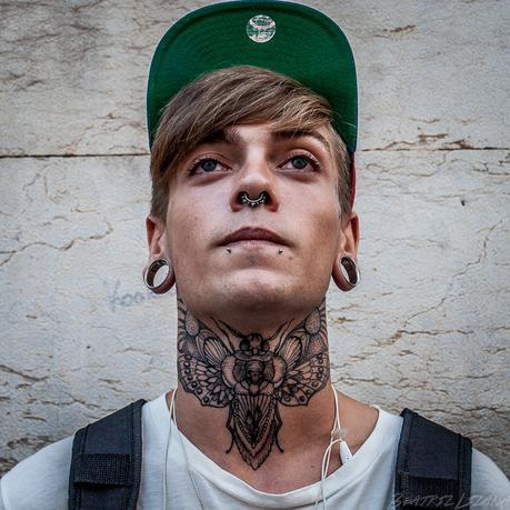 retrato de Óscar con un tatoo de una mariposa enorme en el cuello