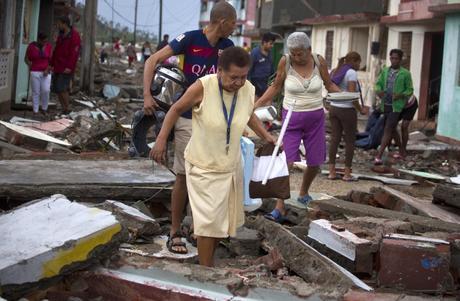 People carry some of their belongings through the rubble of a street after the passing of Hurricane Matthew in Baracoa, Cuba, Wednesday, Oct. 5, 2016.  The hurricane rolled across the sparsely populated tip of Cuba overnight, destroying dozens of homes in Cuba's easternmost city, Baracoa, leaving hundreds of others damaged. (AP Photo/Ramon Espinosa)