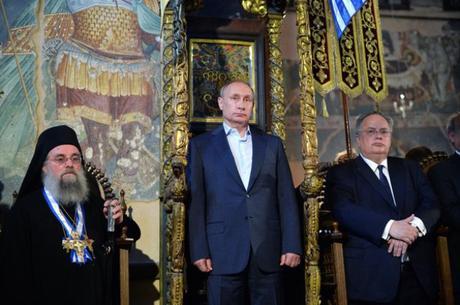 Putin flanqueado por el protos y el Ministro Griego de Asuntos Exteriores durante un servicio religioso en Karyes. Imagen: Alexei Druzhinin. Daily Mail