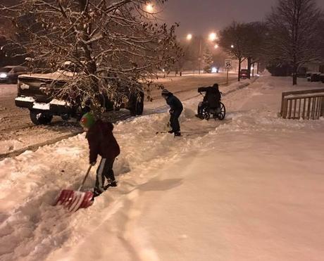 Niños se detienen para ayudar a un hombre en sillas de rueda en la nieve