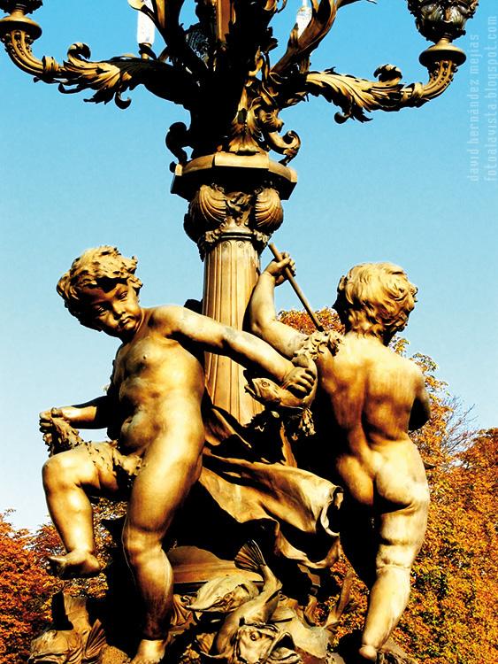 Fotografía de conjunto escultórico de dos niños, que parecen amorcillos, con peces alrededor de una farola sobre el puente de Alejandro III, de París (Francia)