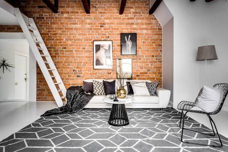 Un ático entre vigas de madera y paredes de ladrillo visto
