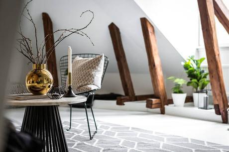 Un ático entre vigas de madera y paredes de ladrillo visto