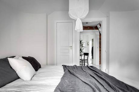 Un ático entre vigas de madera y paredes de ladrillo visto