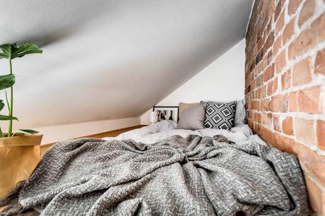 Un ático entre vigas de madera y paredes de ladrillo visto