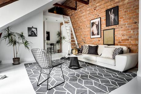 Un ático entre vigas de madera y paredes de ladrillo visto