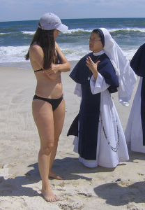 Una monja conversa con una chica en bikini en la playa.
