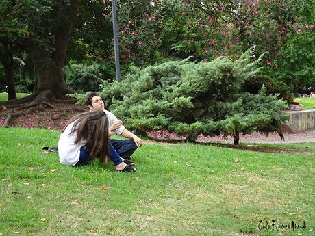 Joven pareja sentada en el césped rodeados de vegetación.
