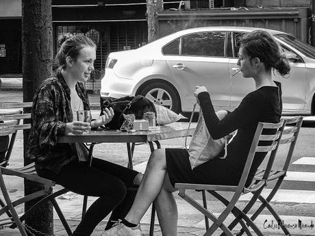 Blanco y  Negro.dos jóvenes sentadas en una mesa de bar en la vereda charlando.