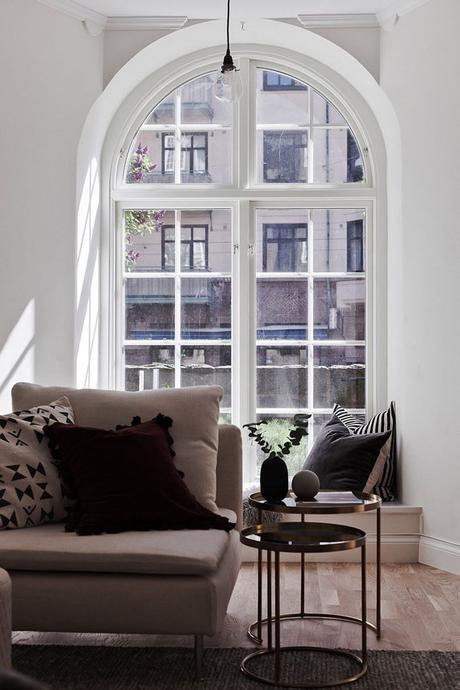 zona de estar, diván con cojines, des mesas nido de cristal y metal dorado