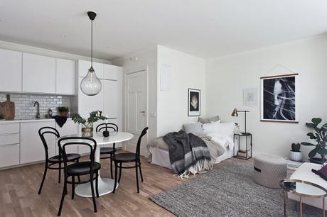 zona de comedor: mesa redonda en blanco con cuatro sillas en negro