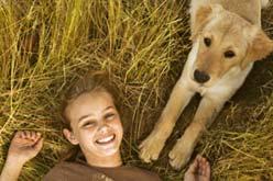 Foto de una niña feliz despertando junto a un perro