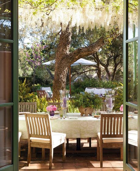 Comedor exterior con vistas al jardín con muebles de madera, portavelas y flores 362777