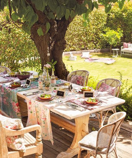 Comedor de exterior con vistas al jardín, suelo y muebles de madera y fibra vegetal, manteles vintage de flores 368067