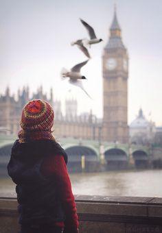 Muchacha joven con un abrigo rojo y sombrero de lana roja ve cómo dos gaviotas sobrevuela el Támesis. Al fondo, el Big Ben