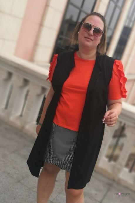 look talla grande curvy con camiseta naranja con volantes en las mangas de primark con falda cuadros vichy y sneakers zapatillas de deporte blancas y maxi chaleco negro de asos para un outfit de verano