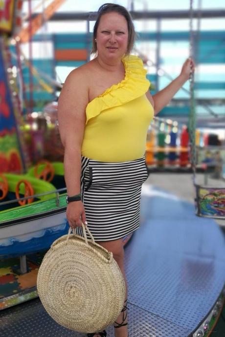 look verano con body amarillo con volantes de primark con falda de rayas y capazo redondo de mimbre y sandalias negras en un carrusel